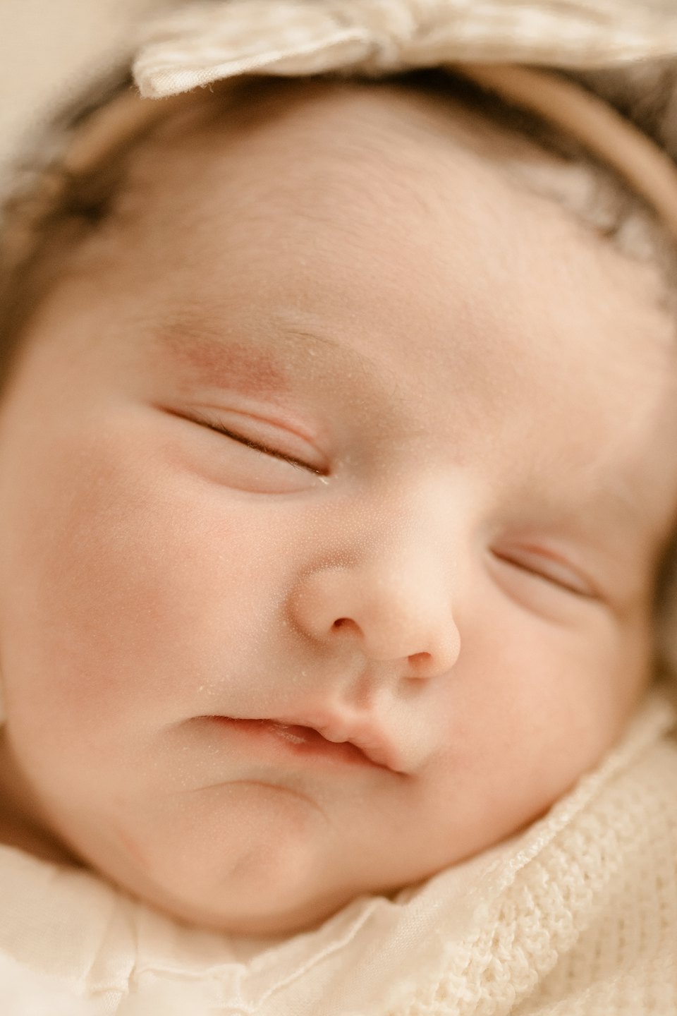 Una neonata dorme con un cerchietto con fiocco.