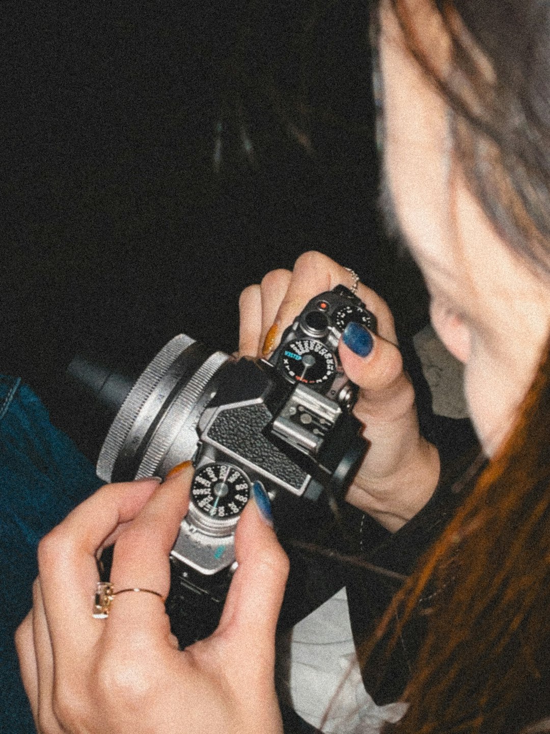 Mani che regolano le impostazioni di una macchina fotografica vintage.